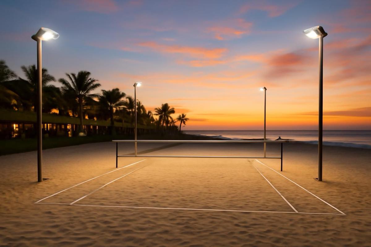 Quadra de beach tennis em resort com iluminação LED e área drenada no entardecer.