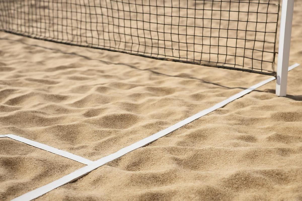 Quadra de beach tennis com areia fina e bem nivelada, sem jogadores, sob luz natural.
