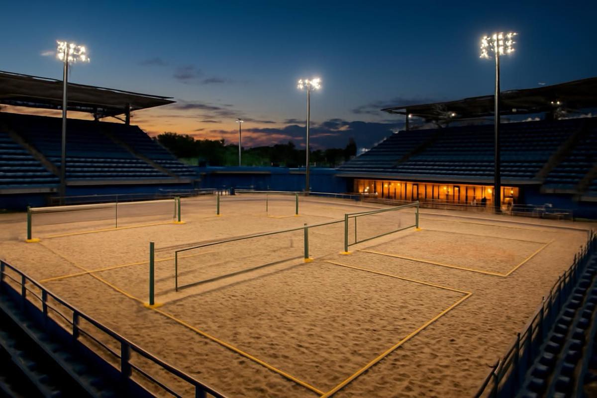 Arena de beach tennis ao entardecer com quadras iluminadas e estrutura de convivência