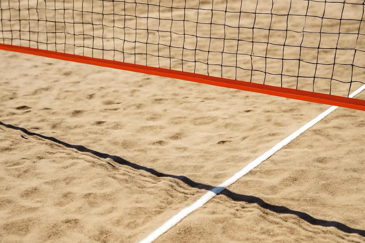 Quadra de futevôlei com areia, rede e marcações oficiais em dia ensolarado
