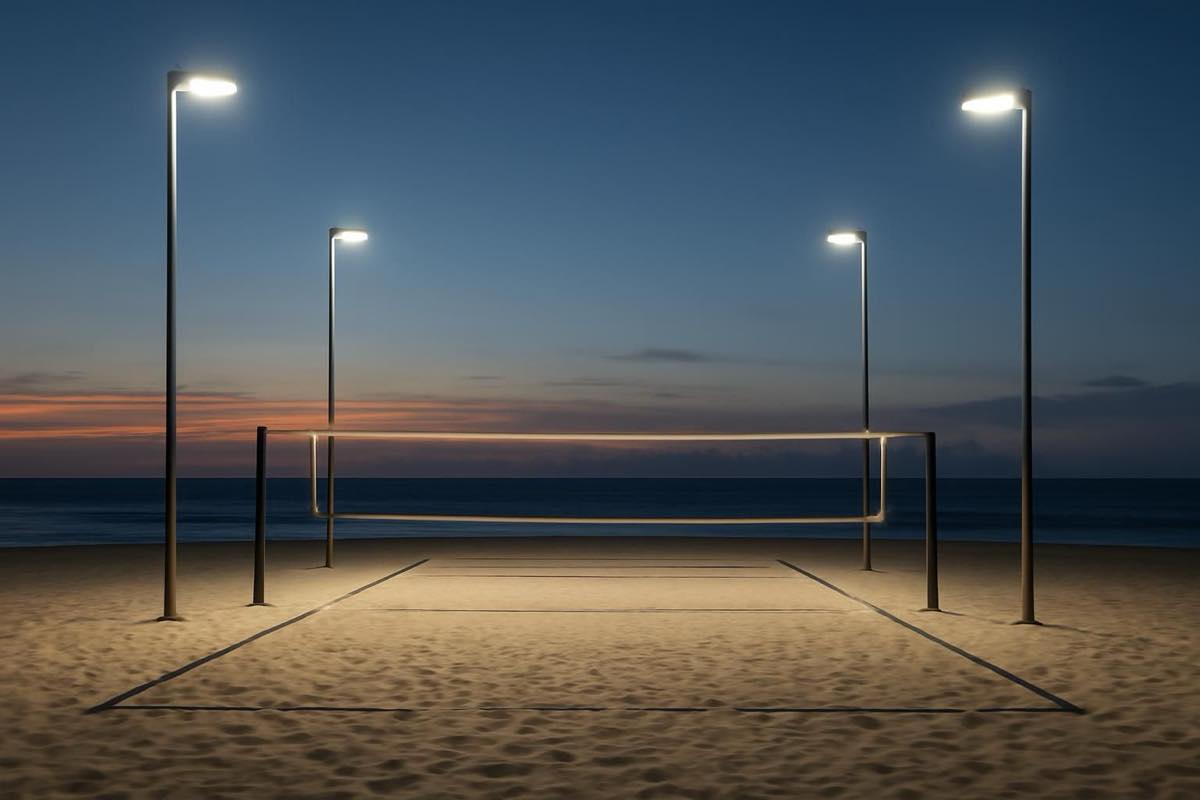 Quadra de beach tennis iluminada por postes laterais com refletores LED, em luz uniforme ao entardecer.