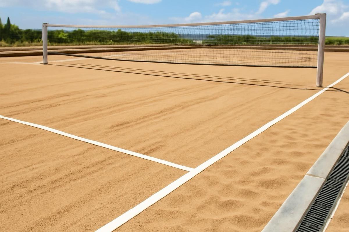 Quadra de beach tennis recém-construída, com areia uniforme e sistema de drenagem visível.