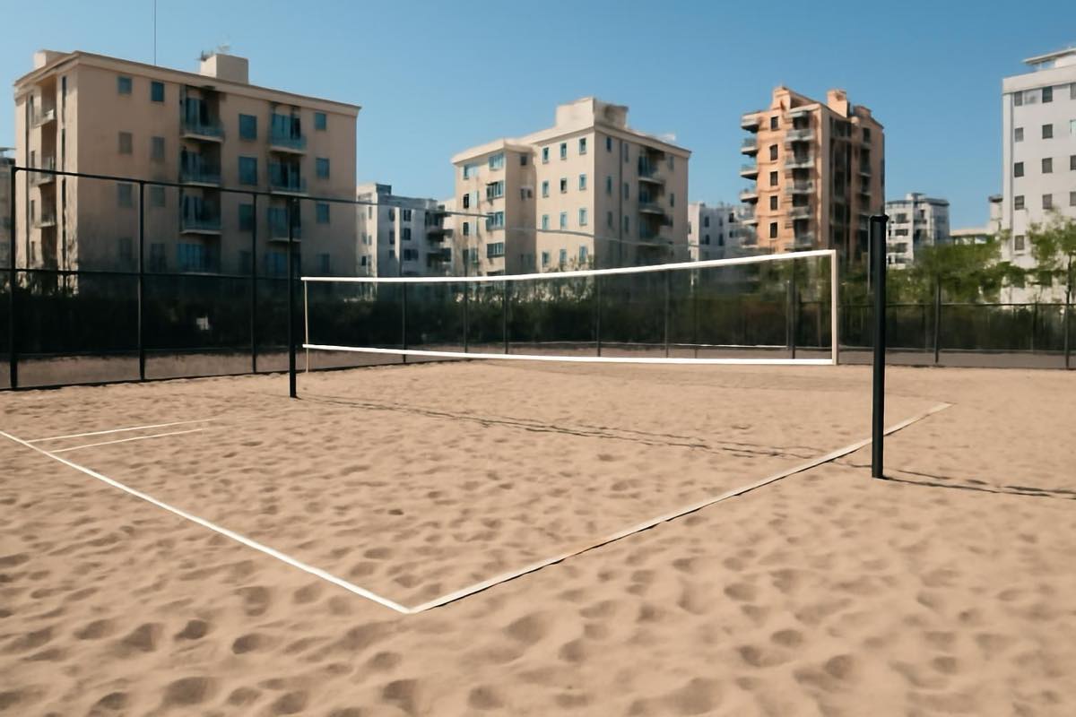 Quadra de beach tennis residencial com areia e demarcações, vista externa sem pessoas.