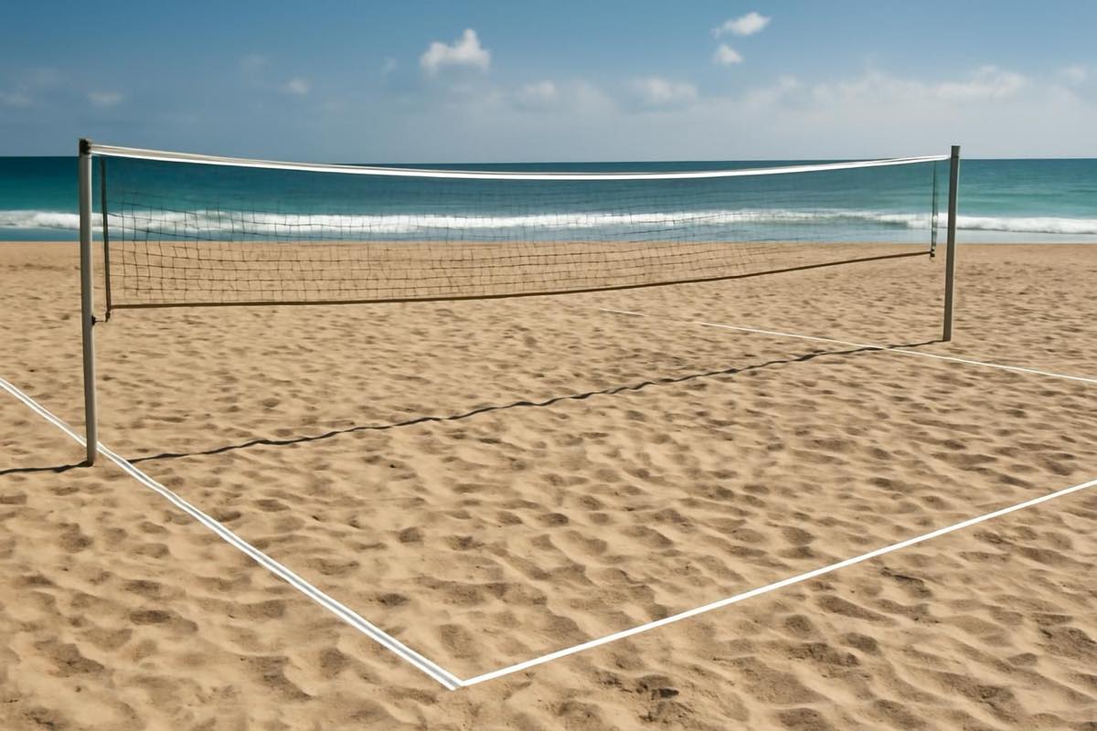 Quadra oficial de beach tennis com rede e linhas demarcadas na areia, ao sol.