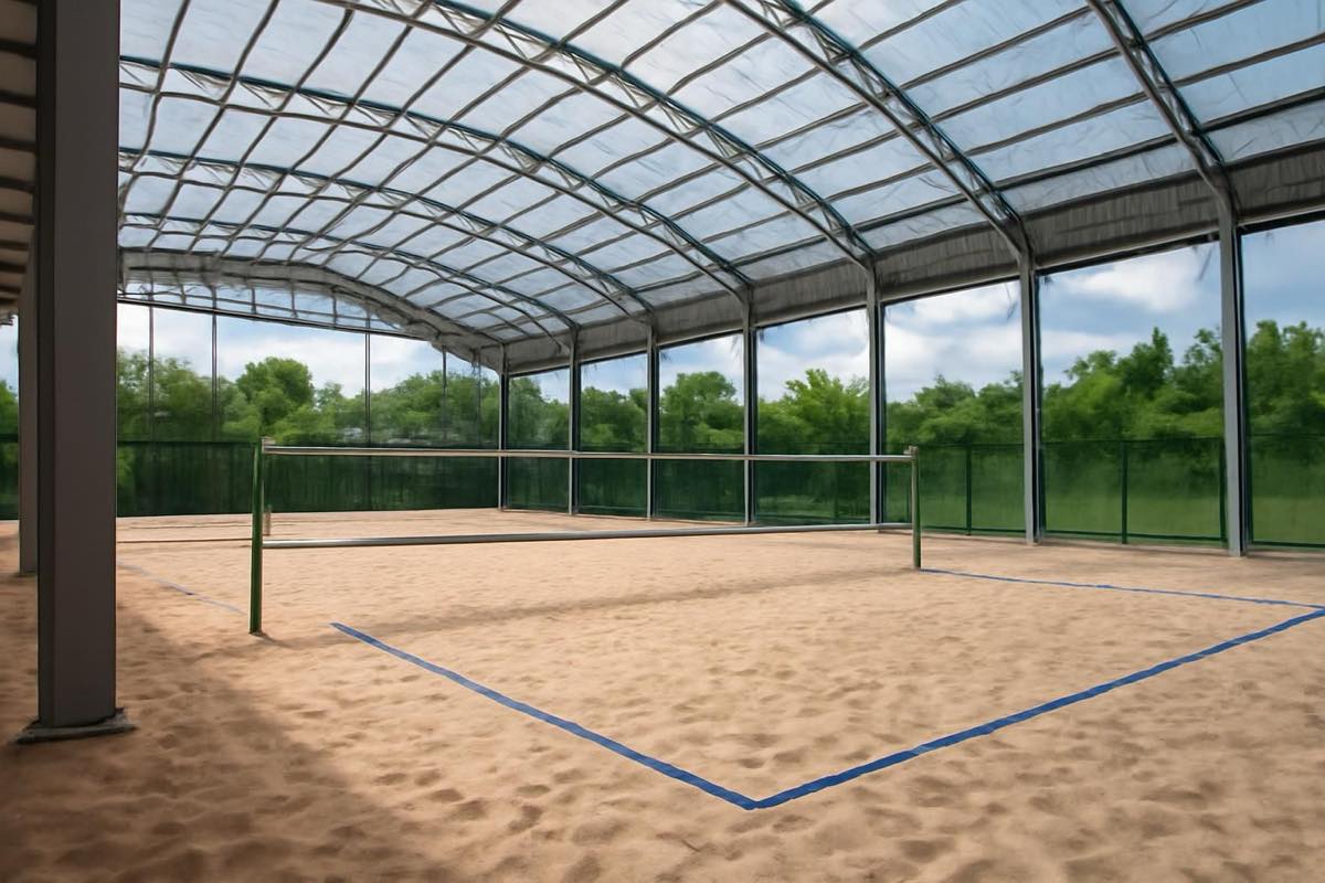 Quadra de beach tennis coberta com pé-direito alto e ventilação adequada, areia bem preservada.