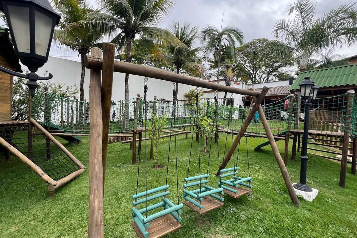 Playground de madeira com balanços vazios no gramado do Espaço Martinica, em Sorocaba